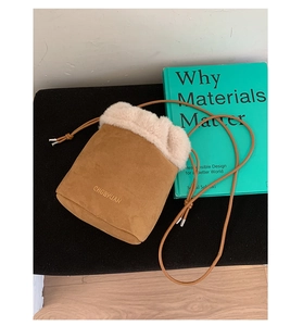 Detail of brown suede bucket bag with beige faux fur trim and leather shoulder strap