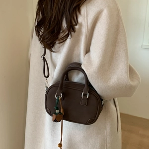 Detail of dark brown leather mini Boston bag with floral charm on stylish wool coat