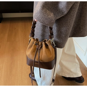 Detail of vintage bucket bag with woven handle and contrast suede leather texture