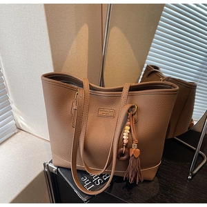 Detail of dark brown tote bag with lychee grain leather texture and tassel charm