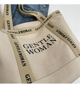 Dettaglio della borsa tote in tela beige con logo nero e trama del tessuto fitta