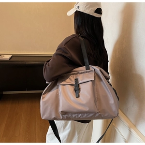 Detailed view of a dusty pink large travel tote bag worn by a model in casual setting