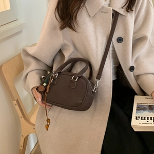 Detail view of dark brown Boston handbag with elegant wood bead tassel and leather texture