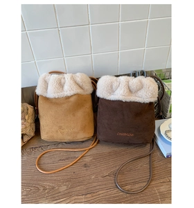 Detail view of suede bucket bags with fuzzy faux fur trim and elegant brand embroidery