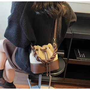 Detail of two-tone bucket bag with braided handle and drawstring closure for women