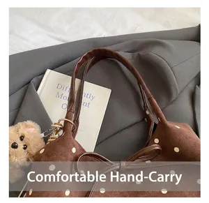 Detail view of brown polka dot canvas tote handle with cute plush bear charm accessory