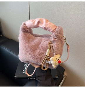 Dettaglio della borsa in ecopelliccia rosa con manico in pelle arricciata e ciondolo