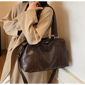 Detailed view of dark brown PU leather tote bag with wide shoulder strap on a model