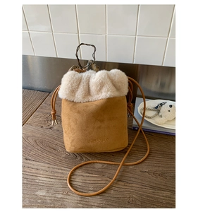 Detailed macro view of the brown suede bucket bag with plush faux fur trim and drawstring