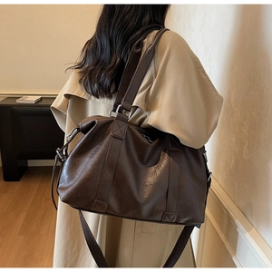 Detail of dark brown faux leather tote bag with adjustable strap on trench coat model
