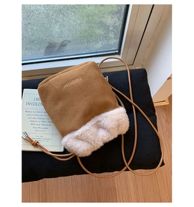 Detail of a brown suede bucket bag with beige faux fur trim and embroidered logo