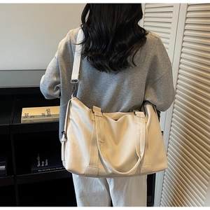 Detail of large beige tote bag showing soft leather texture and adjustable strap
