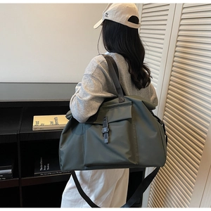 Detail view of large olive green travel tote bag with flap pockets and adjustable straps