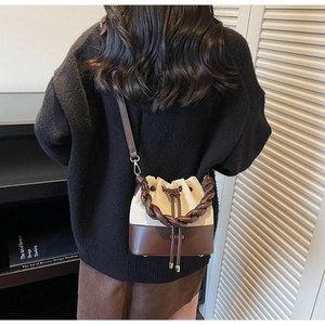 Detailed view of bicolor bucket bag with thick woven handle and drawstring closure