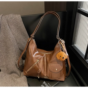 Detail of a brown PU shoulder bag featuring functional pockets and a cute puppy plush charm