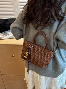 Braune gesteppte Beuteltasche mit Lederriemen und Holzperlen am Modell getragen