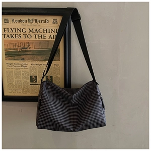 Detailed shot of a black and white checkered crossbody bag with adjustable wide strap