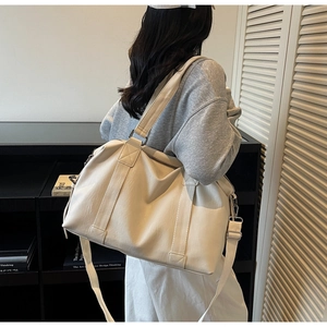 Detailed view of cream-white PU leather travel tote with thick handles and silver hardware