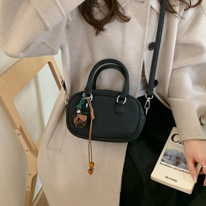 Detail of black Boston bag featuring a matte texture with a brown acorn charm decoration