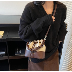 Detail of a color-block bucket bag with a braided leather handle and drawstring closure