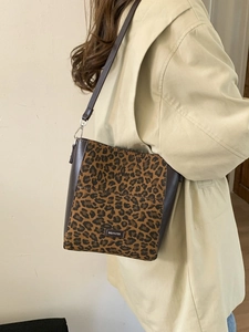 Leopard print bucket bag with faux horsehair and leather trim worn by model in trench coat