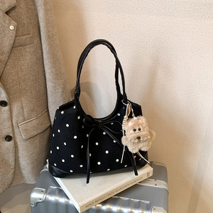 Dettaglio borsa tote retrò a pois con finiture in pelle e ciondolo a forma di cane