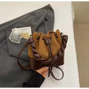 Detail of two-tone bucket bag featuring braided handle and suede leather texture