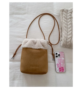 Macro detail of brown suede bucket bag with white faux fur trim and drawstring closure