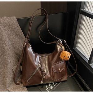 Detail of dark brown faux leather bag with vintage zippers and cute plush charm