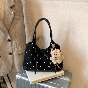Dettaglio della borsa tote in tela a pois con fiocco in pelle e ciondolo orsetto di peluche
