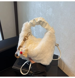 Dettaglio borsa di peluche bianca con manico a pieghe crema e ciondolo a forma di cartone