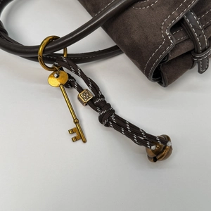 Detailed close-up of retro key pendant on a brown suede crossbody square handbag