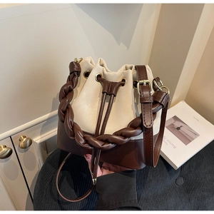 Detailed view of bicolor bucket bag with beige leather, drawstring and braided handle