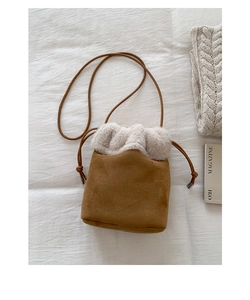 Detail of a brown suede bucket bag featuring plush faux fur trim and drawstring strap