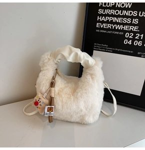 Dettaglio della borsa a mano in peluche crema con manico in PU e ciondolo decorativo