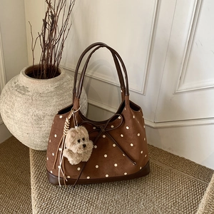Dettaglio borsa tote marrone a pois con fiocco in pelle e ciondolo a forma di cane