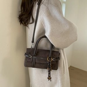 Detail of dark brown suede handbag with white contrast stitching and long woven tassels