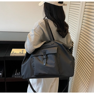 Side view of large black nylon travel bag with buckle pocket on minimalist background