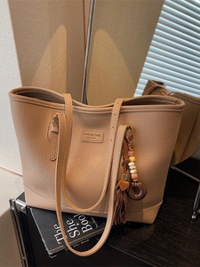Chic light camel litchi leather tote bag with retro tassel charm and slim shoulder straps