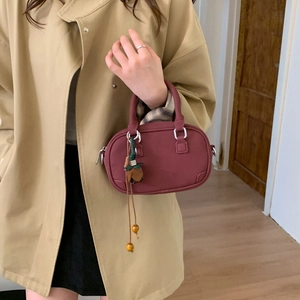 Detail of burgundy leather Boston handbag with tassel charm and silver hardware accents