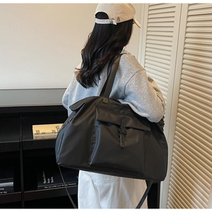 Close-up of black nylon travel bag with buckle flap pocket and durable hand straps