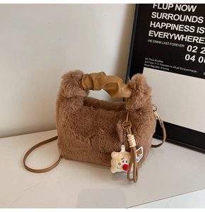 Dettaglio della morbida trama in peluche marrone e del manico in pelle della borsa