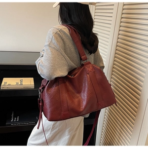 Detail view of burgundy leather tote bag with sturdy handles and adjustable strap
