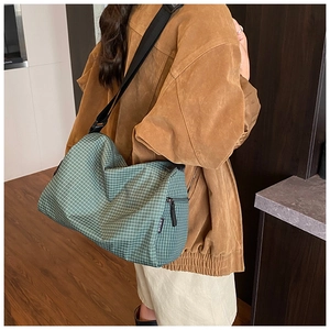 Close-up of green checkered crossbody bag with adjustable wide strap and woven fabric texture