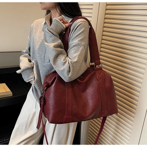 Detail of burgundy leather travel tote bag with top handles and adjustable shoulder strap