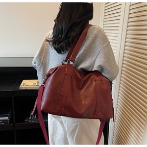 Detail of dark red leather tote bag with fabric shoulder strap and large capacity design