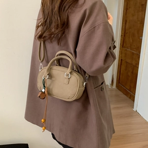Detail of khaki mini Boston bag with matte PU leather and wooden bead charm on shoulder