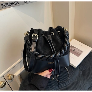 Detail of black mixed-texture bucket bag with woven handle and gold-tone hardware