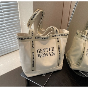 Dettaglio della borsa tote in tela crema con tracolle intrecciate e grande logo stampato