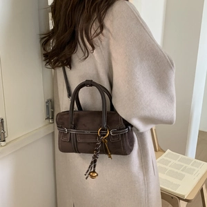 Detail of dark brown suede Boston bag with contrast stitching and gold bell charm